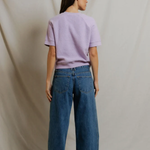 back of woman in short sleeve purple top on draped background 
