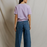 back of woman in short sleeve purple top on draped background 