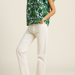 side of woman in green floral blouse on tan background 