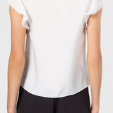 White blouse with lace trim and black shorts on a plain background