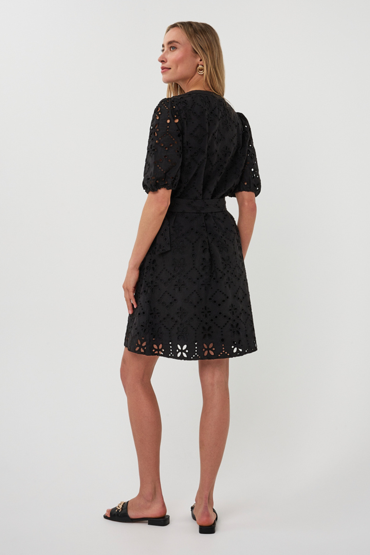 back of woman in black mini dress on white background 