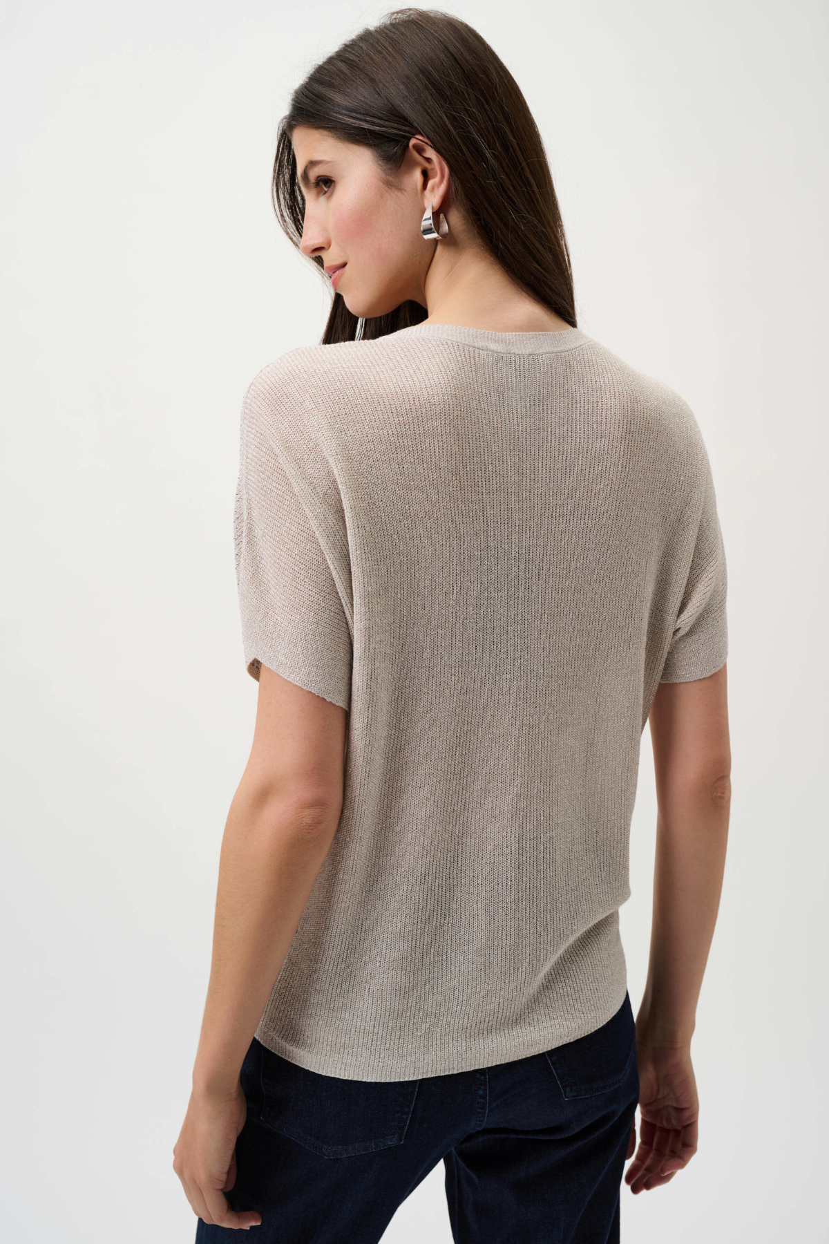 Woman wearing a beige short-sleeve sweater on a white background