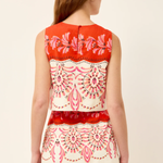Woman wearing a sleeveless top with red and white floral pattern on a beige background