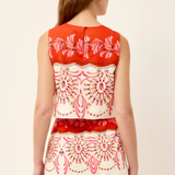 Woman wearing a sleeveless top with red and white floral pattern on a beige background
