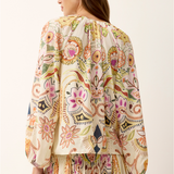 woman in printed long sleeve top from the back on white background 