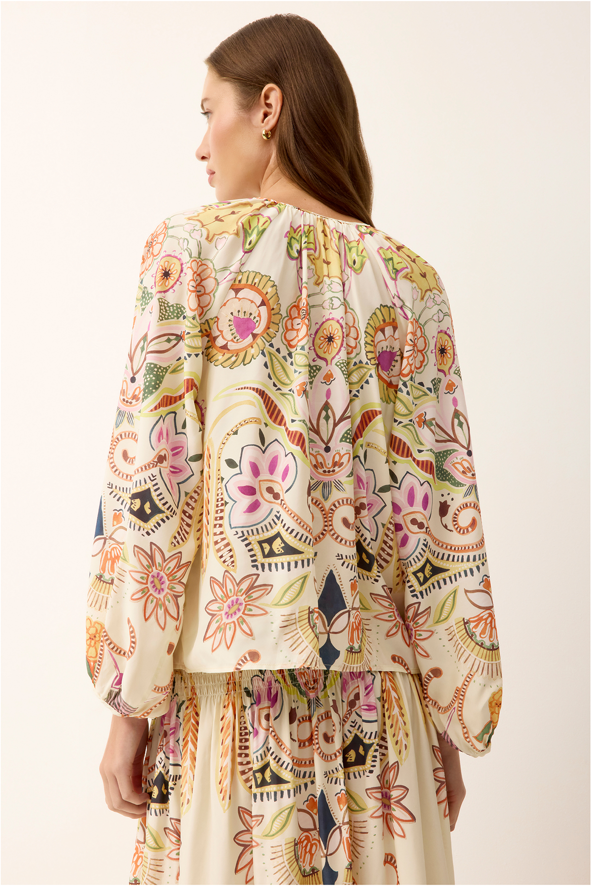 woman in printed long sleeve top from the back on white background 