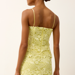 back of woman in yellow lace top on white background 