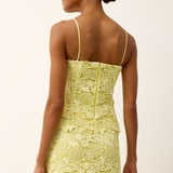back of woman in yellow lace top on white background 
