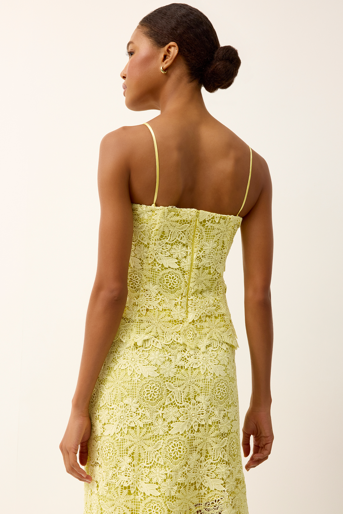 back of woman in yellow lace top on white background 