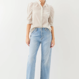 Woman wearing a beige blouse and light blue jeans on a white background