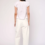 Person wearing a white top and pants on a plain background