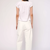 Person wearing a white top and pants on a plain background