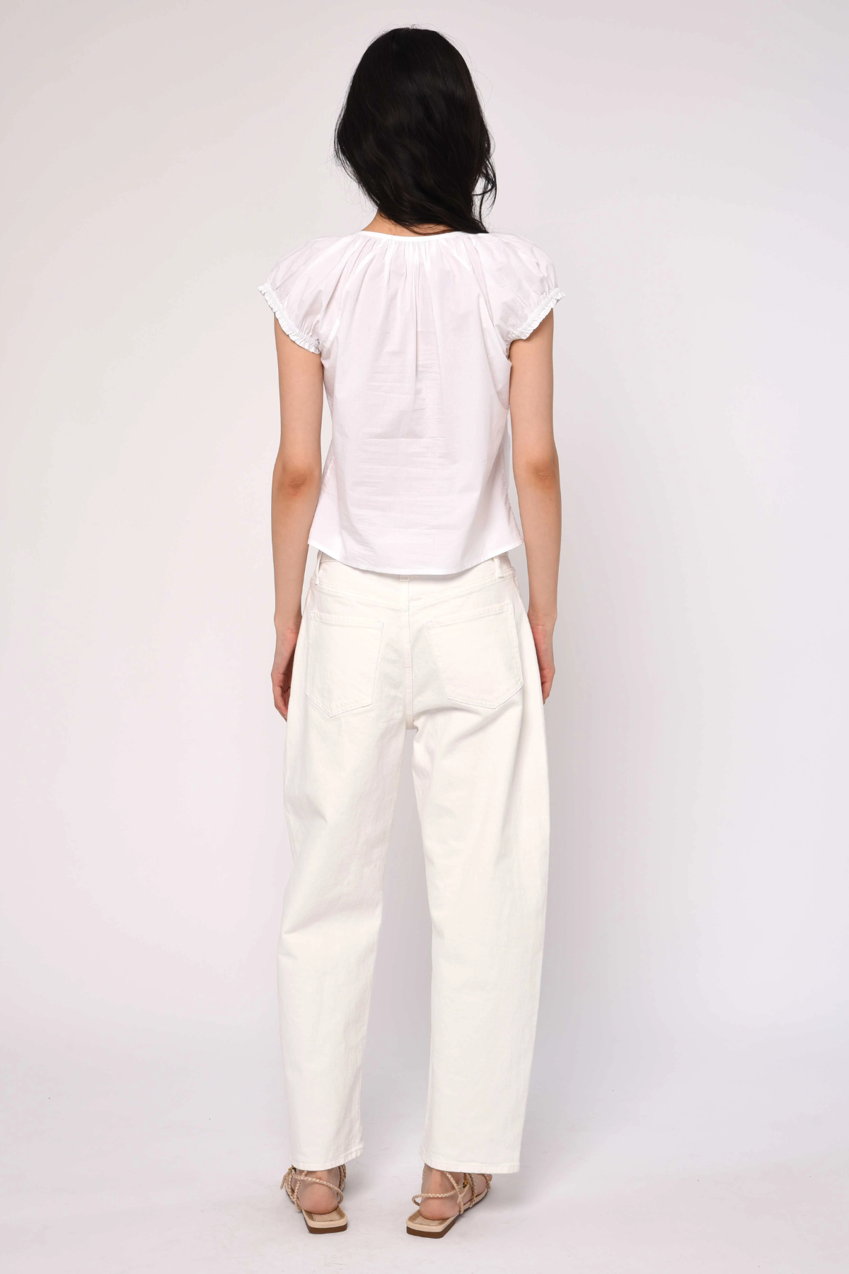 Person wearing a white top and pants on a plain background