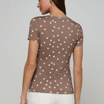 Woman wearing a brown polka dot shirt against a gray background