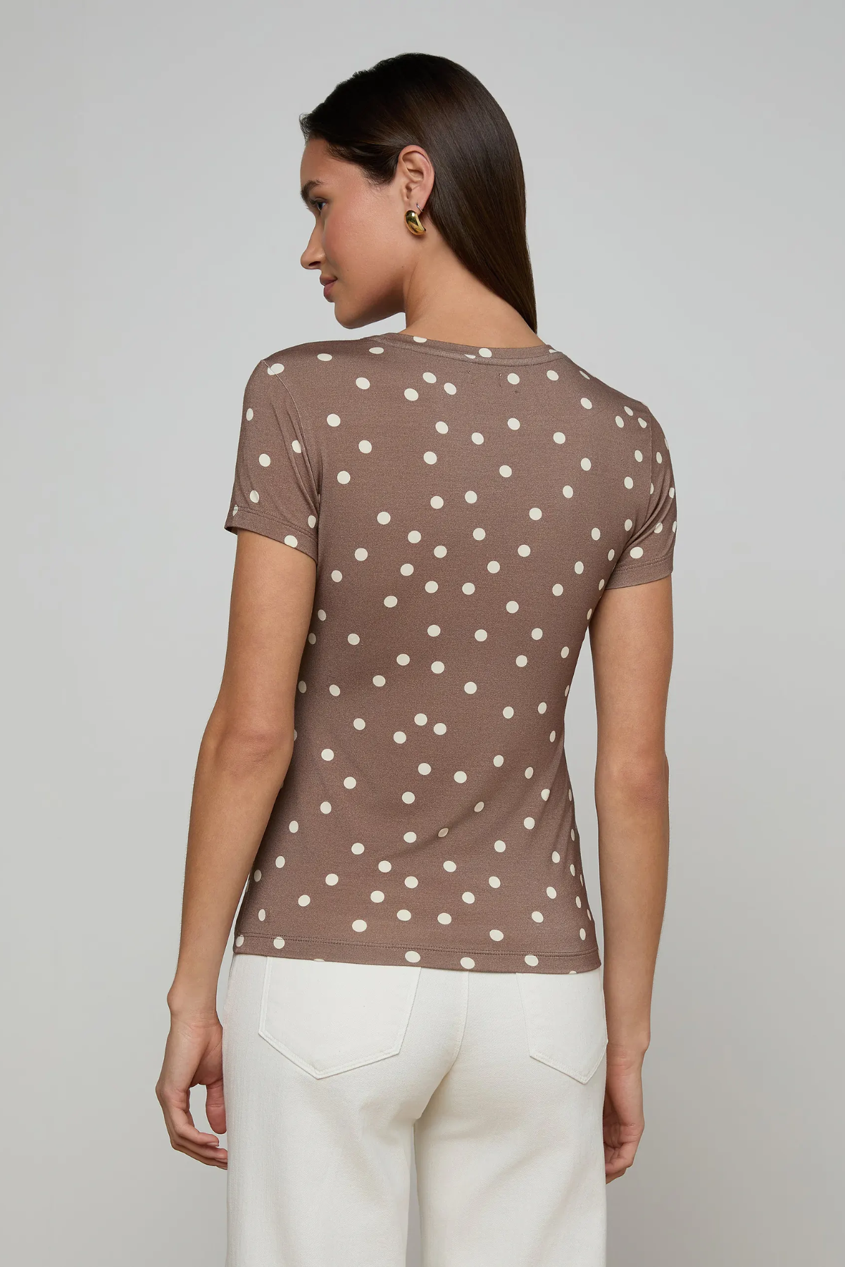 Woman wearing a brown polka dot shirt against a gray background