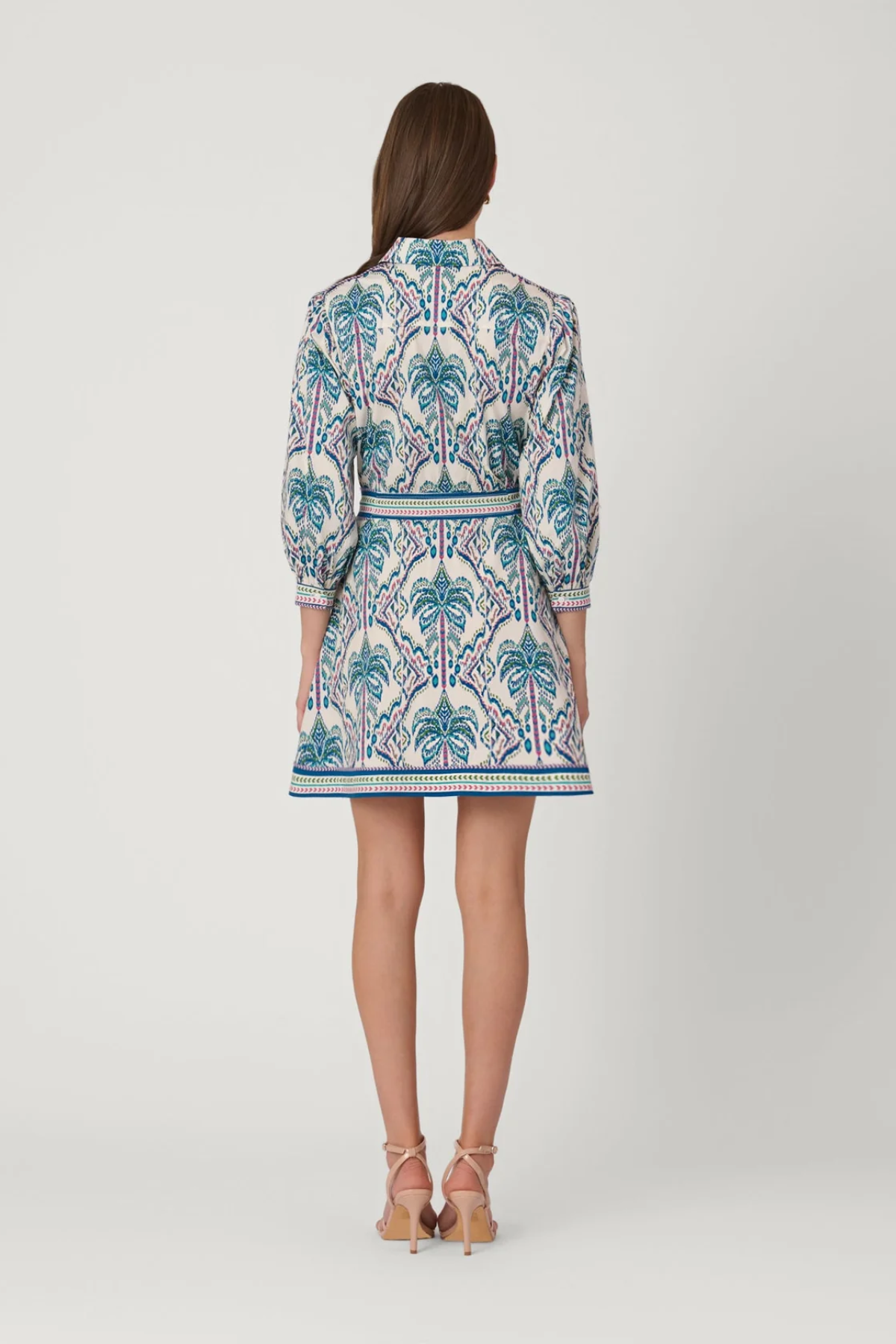 Woman wearing a patterned dress on a white background back view