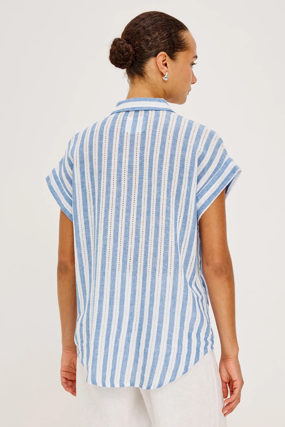 back of woman in blue and white stripe shirt on white background 