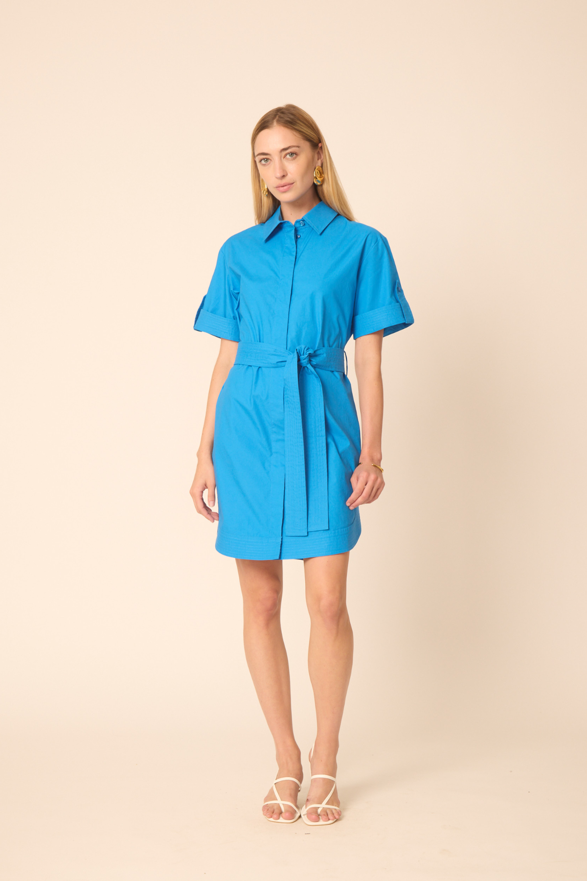 woman in blue mini dress on tan background 