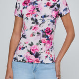 Person wearing a floral t-shirt with pink roses on a plain background