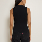 Person wearing a black sleeveless top and black pants against a plain background