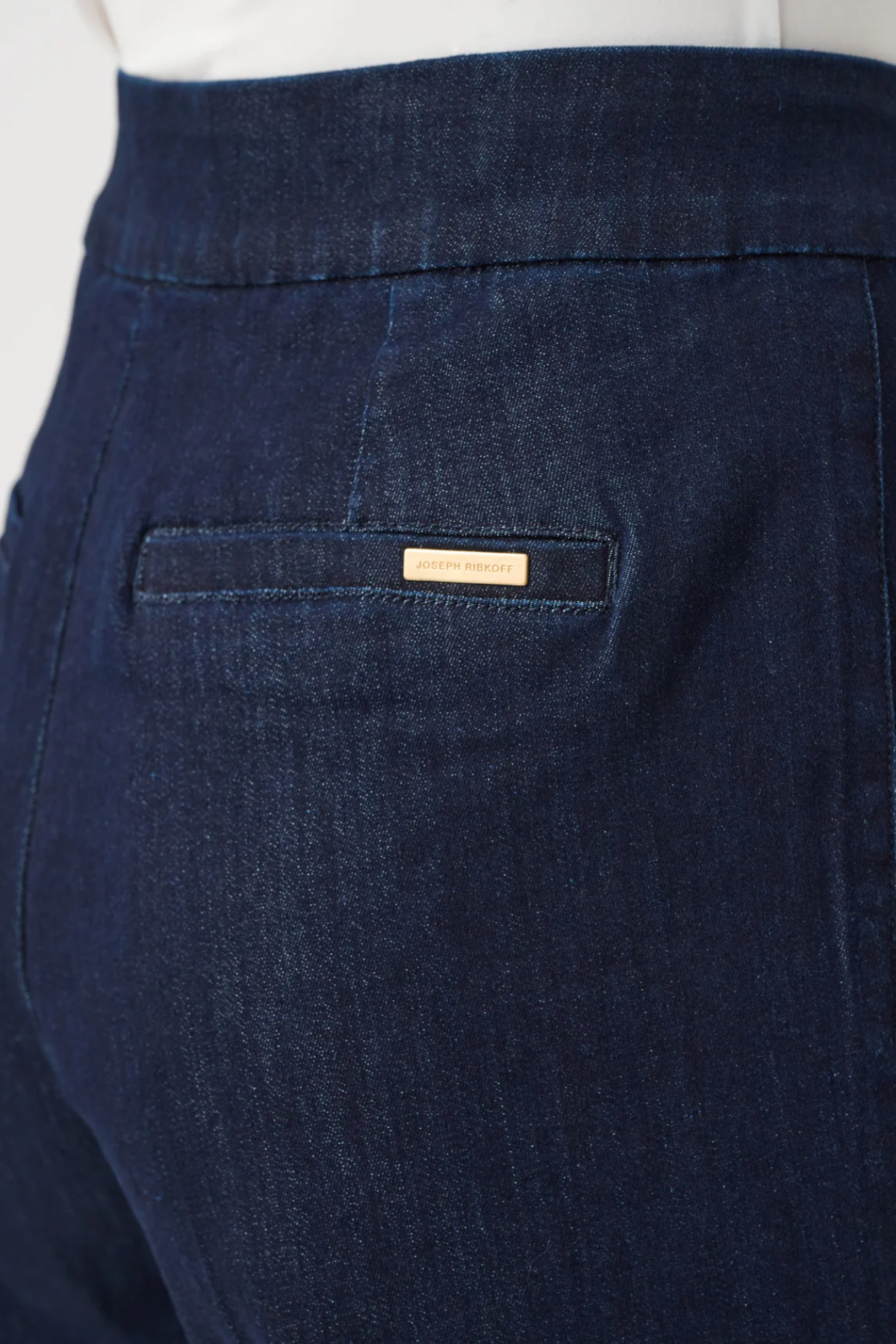 Close-up of dark blue pants with a brand label on the pocket.