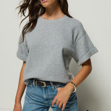 Woman wearing a gray oversized t-shirt and blue jeans against a white background