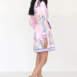 Woman wearing a pink floral dress with beige boots on a white background