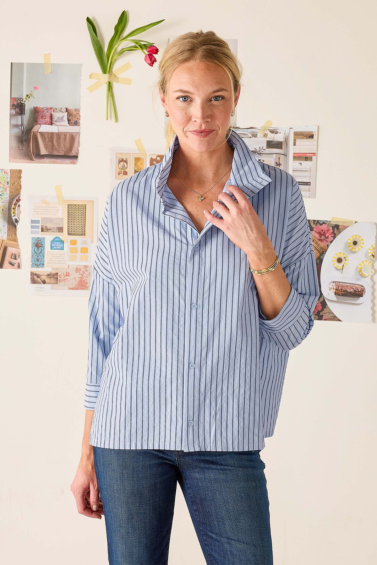 Woman wearing a blue striped shirt in an office setting with bulletin board in the background