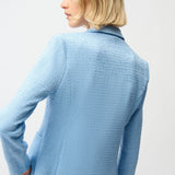 Person wearing a light blue textured jacket on a white background