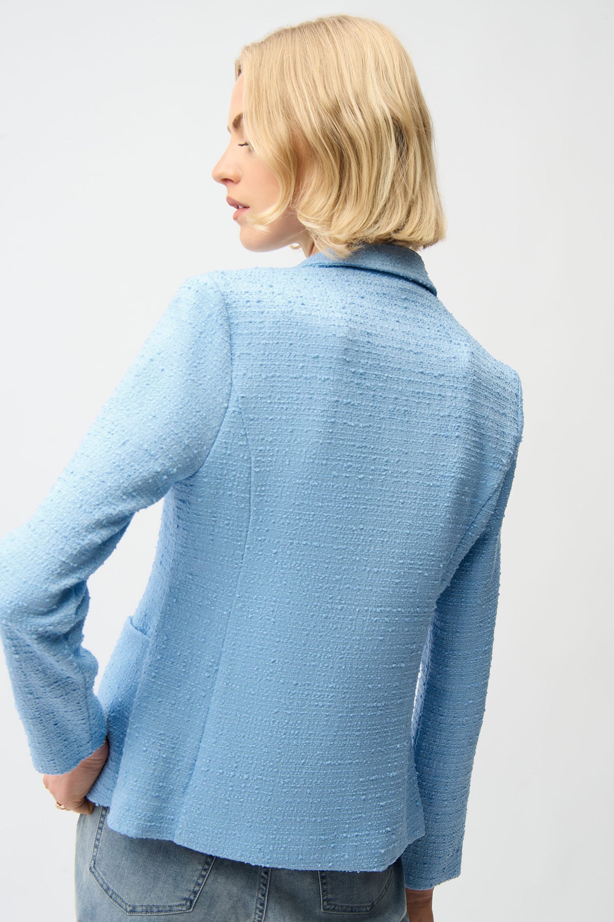 Person wearing a light blue textured jacket on a white background