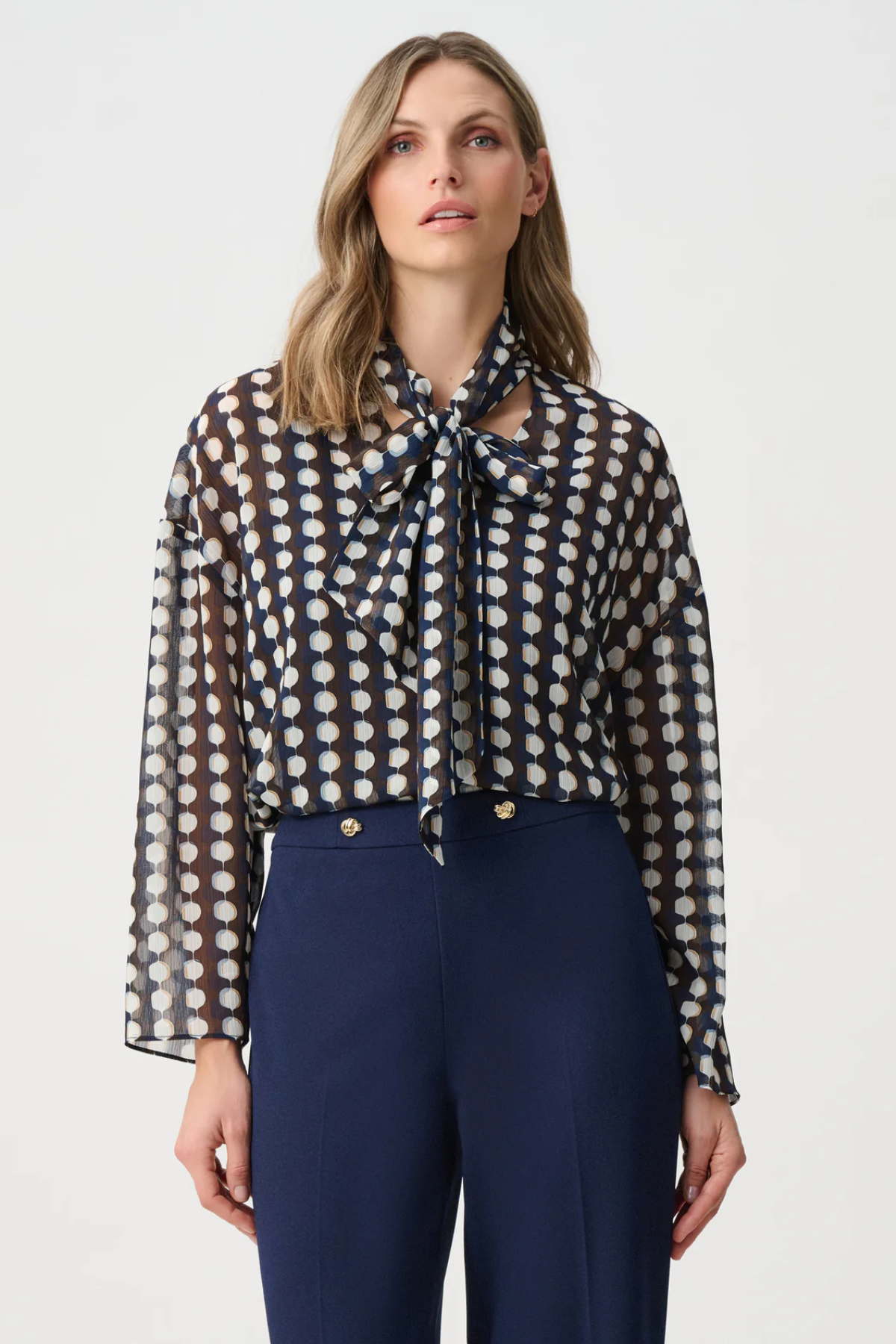 Model wearing a long-sleeve chiffon blouse with a geometric print and tie-neck detail in a relaxed, feminine silhouette.