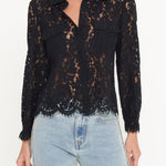 Black lace blouse worn by a person with light blue jeans on a white background