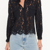 Black lace blouse worn by a person with light blue jeans on a white background