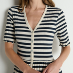 Woman wearing a black and white striped dress against a plain background