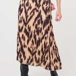 A model wearing a pleated midi skirt with a brown and beige animal print, paired with a brown ribbed top and black ankle boots, shown from the waist down on a white studio background.