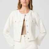 Woman wearing a white denim jacket and shorts on a plain background