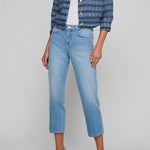 Woman wearing a blue patterned jacket and light blue jeans on a gray background