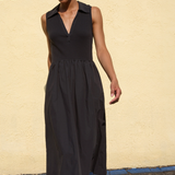 Woman wearing a black sleeveless dress against a beige wall.