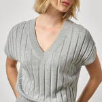 Woman wearing a gray ribbed sweater against a plain background