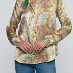 Model wearing printed blouse with jeans on a white background.
