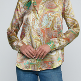 Model wearing printed blouse with jeans on a white background.