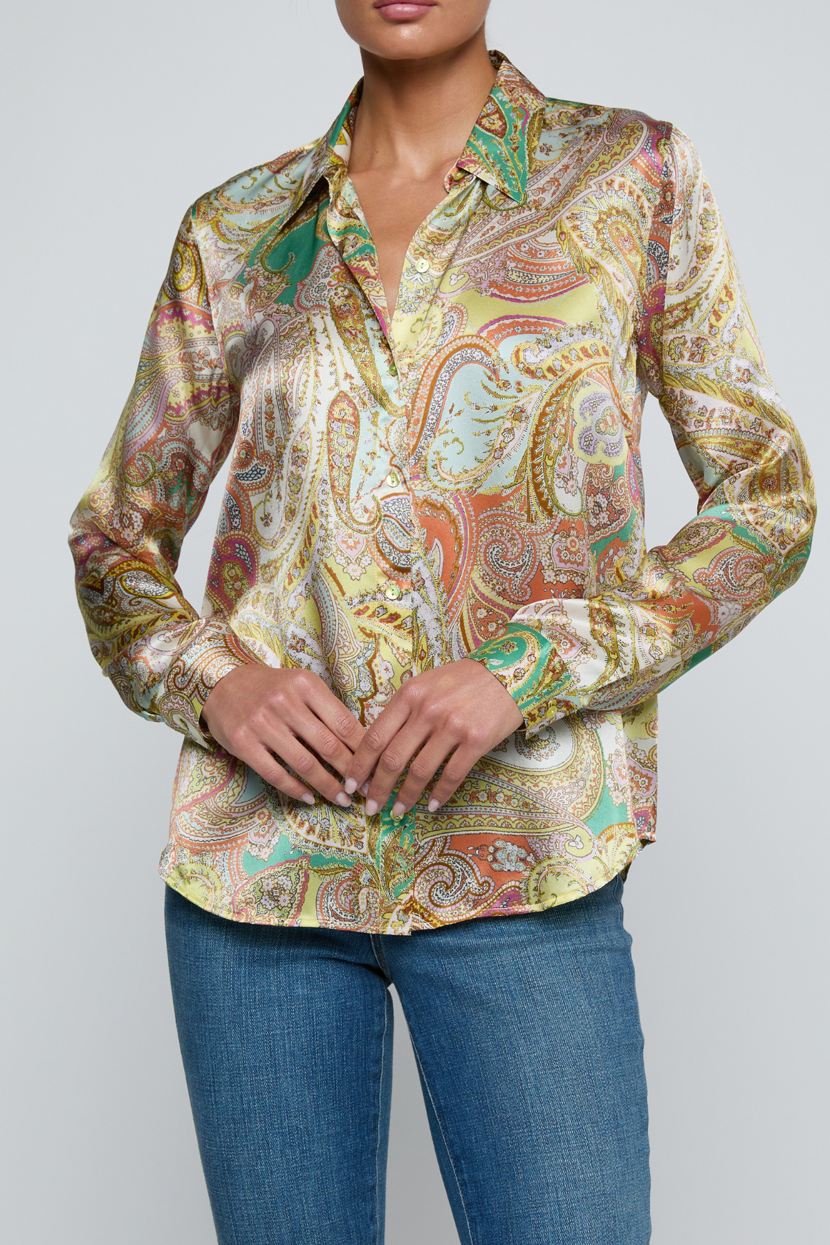 Model wearing printed blouse with jeans on a white background.