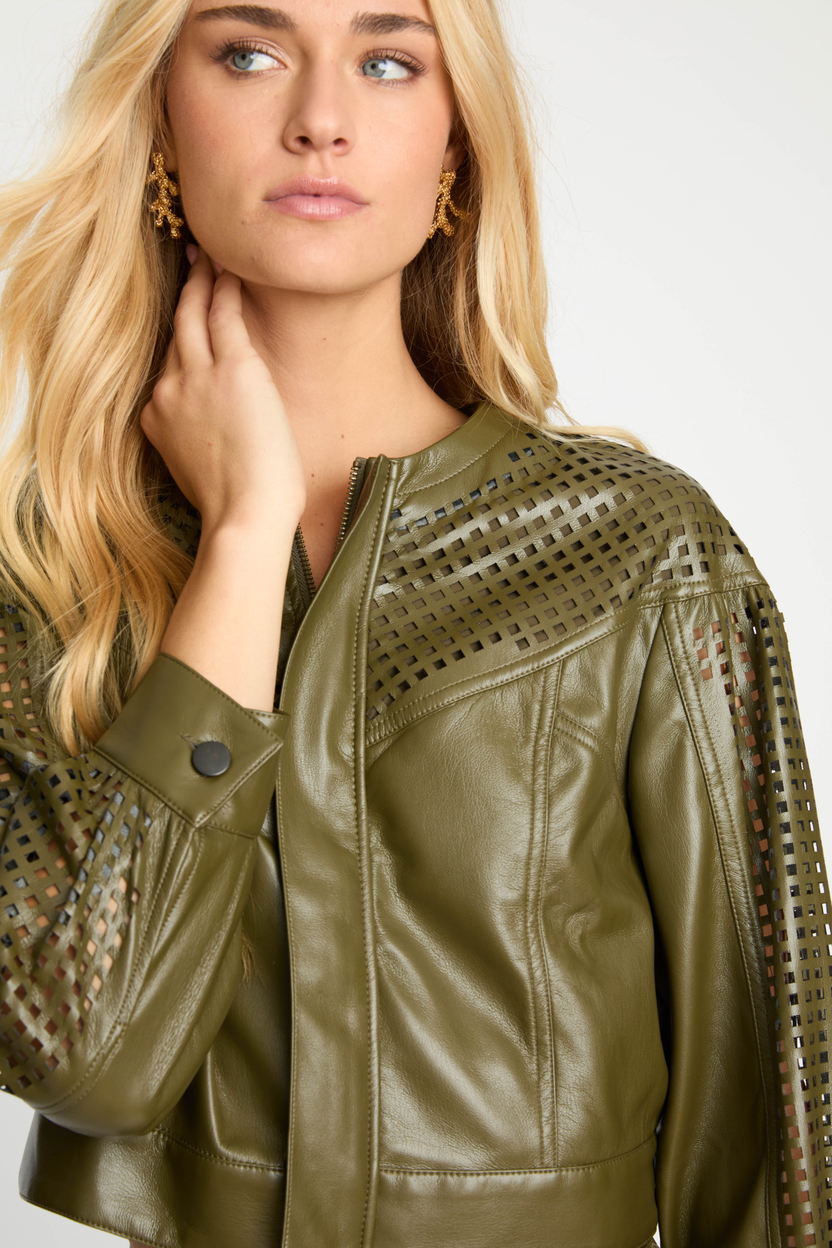 Woman wearing a green leather jacket with cut-out details on a white background