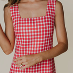 Red and white checkered dress worn by a person on a beige background