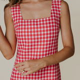 Red and white checkered dress worn by a person on a beige background
