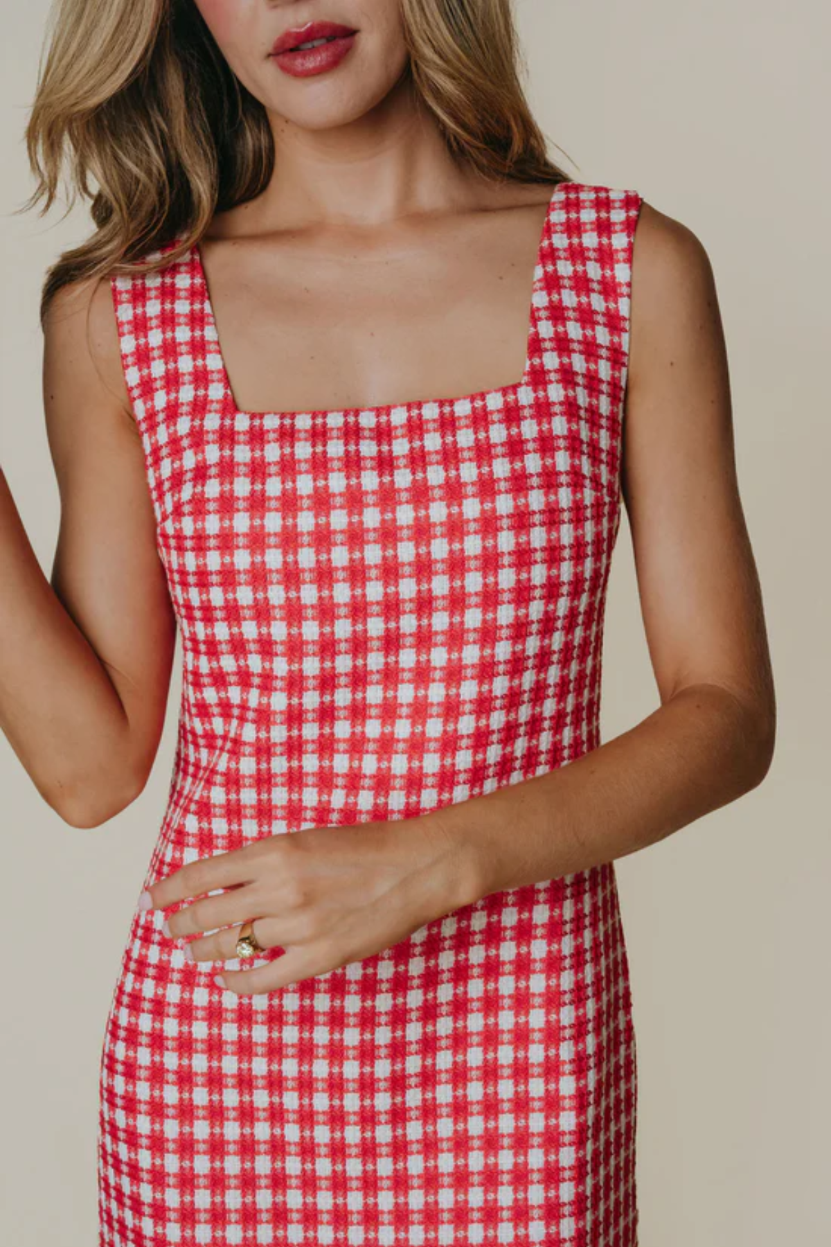 Red and white checkered dress worn by a person on a beige background