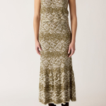 A sleeveless midi dress with a textured, abstract pattern in olive green and cream, worn by a model with dark brown ankle boots against a plain light background.