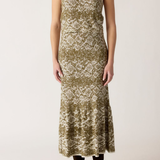 A sleeveless midi dress with a textured, abstract pattern in olive green and cream, worn by a model with dark brown ankle boots against a plain light background.