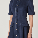 A navy blue short-sleeve button-front dress with structured shoulders and front flap pockets, shown on a model against a light gray studio background.