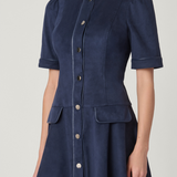 A navy blue short-sleeve button-front dress with structured shoulders and front flap pockets, shown on a model against a light gray studio background.